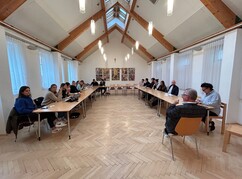 Mehrere Personen um eine u-förmige Tischformation sitzend