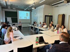 Mehrere Personen um Tische in U-Formation sitzend